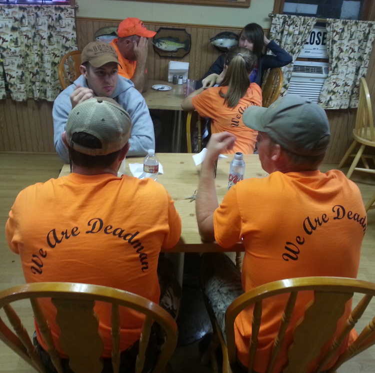 Customers conversing while wearing an orange Deadman Creek Outfitters t-shirt